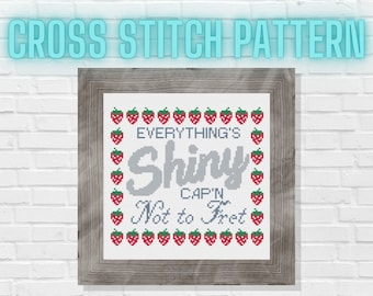 May include: Cross stitch pattern with a gray background and red strawberries around the border. The text reads "Everything's Shiny Cap'n Not to Fret".