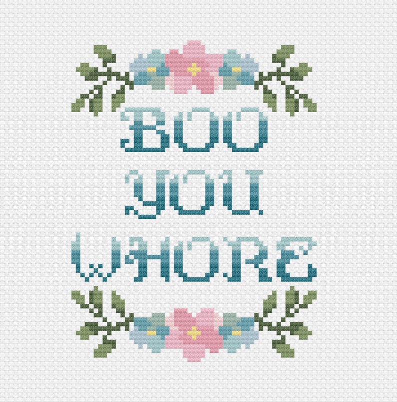May include: Cross-stitch design on white fabric. The text "BOO YOU WHORE" is stitched in blue, with floral accents in pink, blue, and yellow. Green leaves frame the text, creating a decorative, handmade appearance.