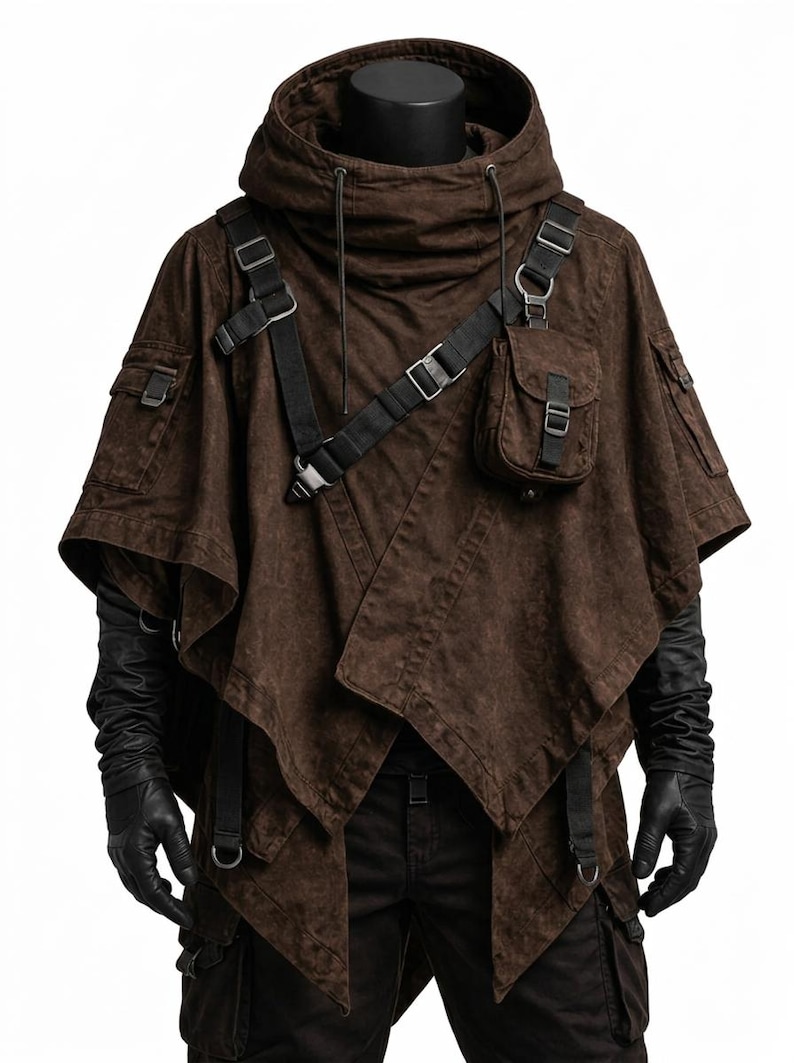 May include: A dark brown hooded poncho featuring black adjustable straps, metal buckles, and a small attached pouch on the chest. The garment has a layered, asymmetrical hemline and is worn over black long-sleeved gloves and dark trousers.