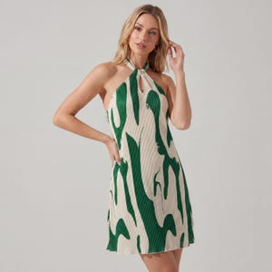 May include: A cream-coloured mini dress with a halter neck and a striking green abstract design. The dress has a keyhole neckline and a pleated texture. The sleeveless dress falls above the knee.