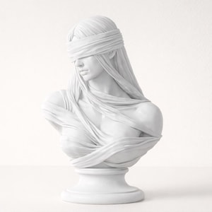 May include: A white bust sculpture of a woman with a blindfold and draped fabric. The sculpture is on a pedestal and has a classical aesthetic. The bust is a monochromatic piece, with soft shadows and highlights.