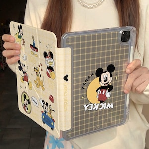 Może przedstawiać: Etui na iPada z Myszka Miki. Przezroczysty tył ma wzór kraty i grafikę Myszki Miki ze słowem "Wicked". Przednia okładka przedstawia różne ilustracje Myszki Miki na beżowym tle.