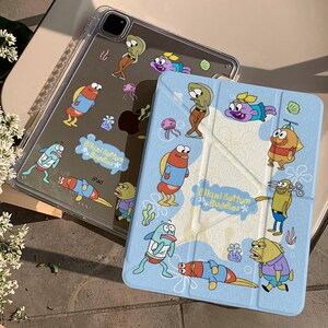 May include: Clear iPad case and light blue iPad cover featuring cartoon fish characters. The clear case has a colorful design with the text "Bikini Bottom Buddies" and "iPad". The light blue cover has a similar design with the same text.