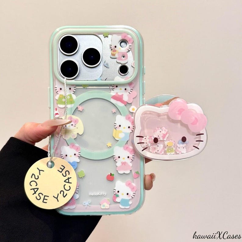 May include: A clear phone case with a mint green border, featuring Hello Kitty designs and a matching pop socket. The case has a circular cutout and a tag that says "Y2CASE". The pop socket is shaped like Hello Kitty with a pink bow.