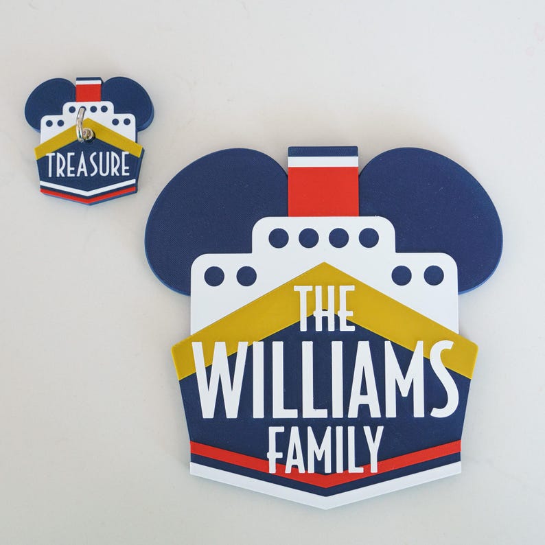 Puede incluir: Un barco de crucero azul y amarillo con el texto "The Williams Family" en la parte delantera. El barco tiene la forma de las orejas de Mickey Mouse.