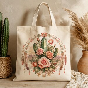 Puede incluir: Una bolsa de tela color crema con un gr&aacute;fico circular central de cactus verdes y rosas rosadas. El dise&ntilde;o incluye elementos de paisaje des&eacute;rtico, patrones geom&eacute;tricos y detalles de plumas colgantes en tonos tierra y rosa suave.