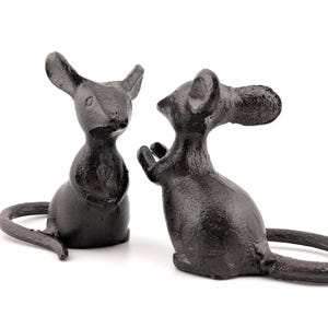 May include: Two dark grey cast iron mouse ornaments. The mice have detailed features, including large ears and long tails. One mouse is upright, and the other appears to be sitting. The ornaments are on a white background.