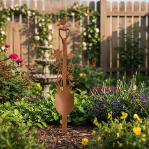 Peut inclure: Un piquet de jardin en m&eacute;tal brun rouill&eacute; en forme de pelle, orn&eacute; de d&eacute;coupes florales et d'un oiseau perch&eacute;. Le piquet est plac&eacute; dans un jardin avec une cl&ocirc;ture en bois et une fontaine. Le piquet mesure environ 100 cm de haut.