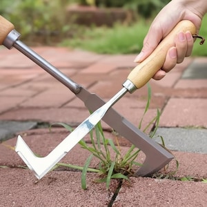May include: Two garden weeding tools with wooden handles and metal blades are shown. One tool has a flat blade, and the other has a V-shaped blade. The tools are on a brick surface with weeds growing between the bricks.