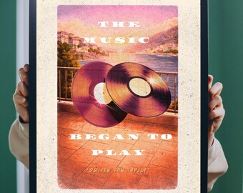 May include: Framed vintage print with two vinyl records and the text "THE MUSIC BEGAN TO PLAY" and "DRIVEN FOR IMPACT." The background depicts a coastal scene with mountains and buildings, in a retro colour palette.