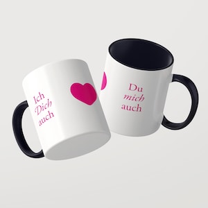 Pu&ograve; includere: Due tazze in ceramica bianca con manici e interni neri. La tazza a sinistra presenta il testo magenta Ich Dich auch e un cuore magenta. La tazza a destra mostra il testo magenta Du mich auch e un grafico a cuore parziale.