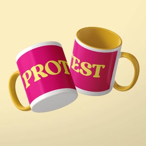 May include: Two ceramic mugs with a bright pink exterior and a yellow interior and handle. The mug on the left features the yellow text PROT, while the mug on the right displays the yellow text EST, creating the word PROTEST when viewed together.