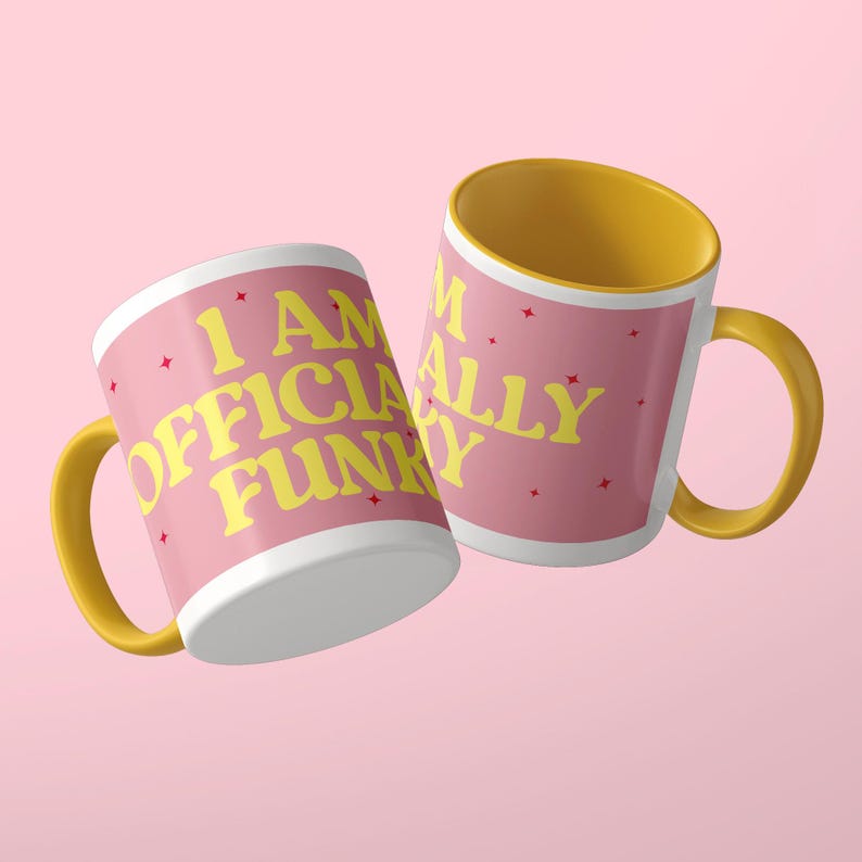 May include: Two ceramic mugs with a pink exterior and a yellow interior and handle. The mugs feature the yellow text "I AM OFFICIALLY FUNKY" printed on the pink surface, accented by small red star-shaped graphics scattered across the design.