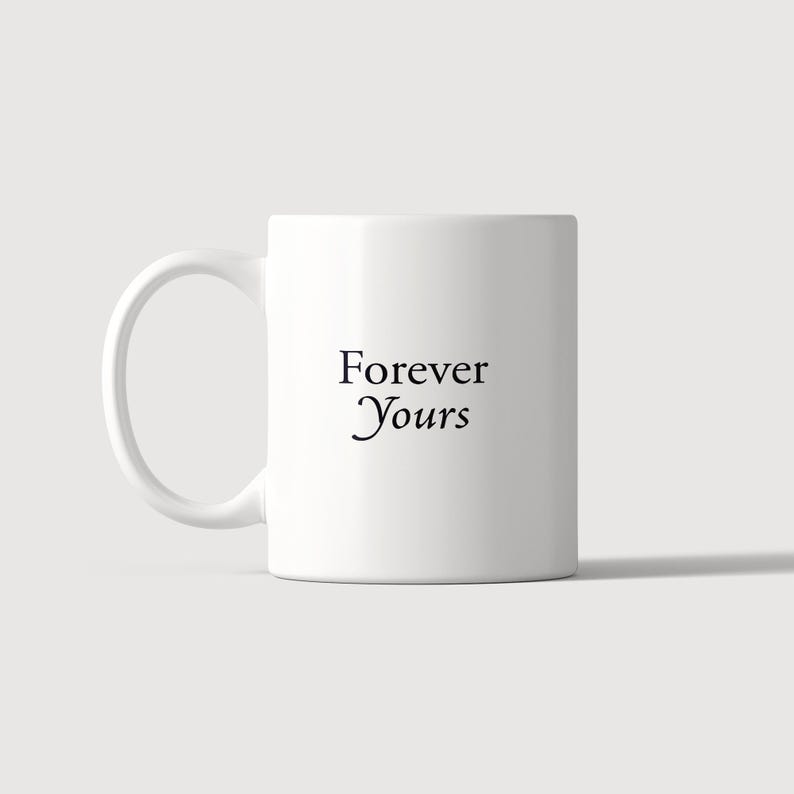 May include: A white ceramic mug featuring a curved handle on the left side. The text Forever Yours is printed in a black serif font on the center of the mug. The design is simple and clean, showcasing a standard cylindrical shape with a smooth finish.