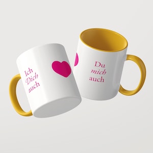 Pu&ograve; includere: Due tazze in ceramica bianca con manici e interni gialli. La tazza a sinistra presenta un cuore rosa e il testo Ich Dich auch. La tazza a destra mostra il testo Du mich auch in lettere rosa. Entrambe hanno una finitura liscia e lucida.