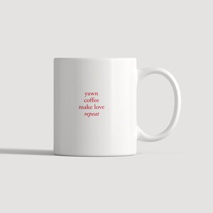 以下が含まれることがあります： 前面に「yawn coffee make love repeat」という赤い文字が中央揃えで積み重ねてプリントされた白いセラミック製のマグカップ。マグカップは滑らかな円筒形の本体と、右側から伸びる湾曲したハンドルを備えています。