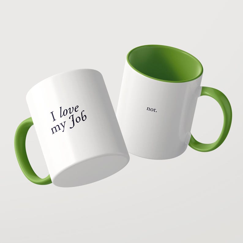 May include: Two white ceramic mugs with bright green interiors and handles. One mug features the black text 'I love my Job' in a serif font, while the other mug displays the word 'not.' in a smaller, simple black font on the side.