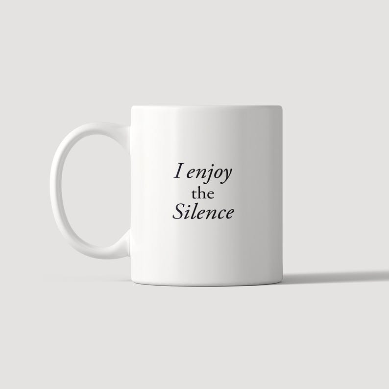 May include: A white ceramic mug with a curved handle featuring the black printed text I enjoy the Silence centred on the front. The mug has a smooth, cylindrical body and a clean, minimalist design suitable for holding hot or cold beverages.