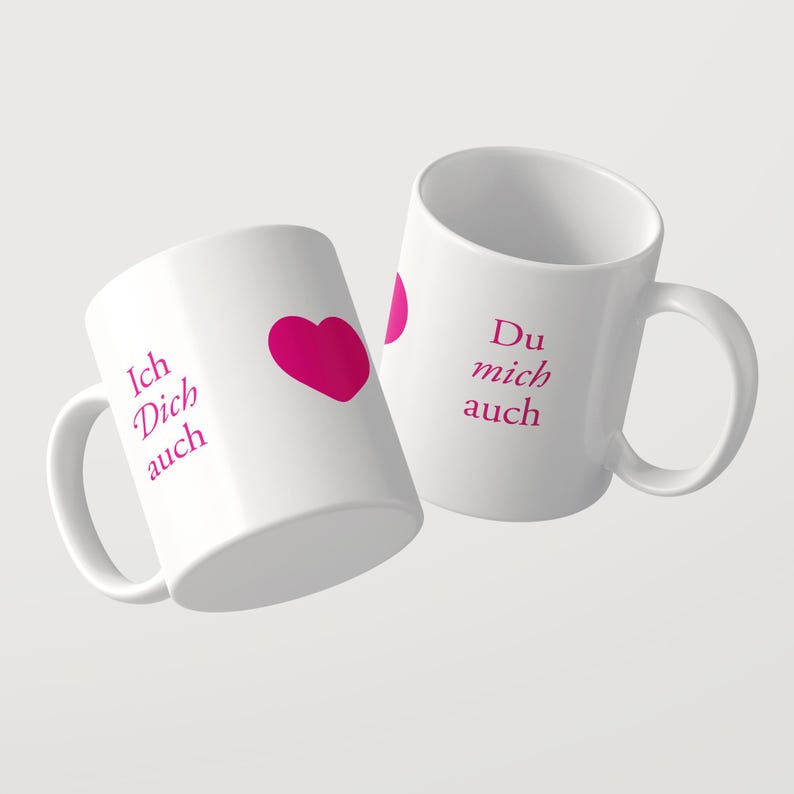 Pu&ograve; includere: Due tazze in ceramica bianca con testo rosa e un grafico a forma di cuore rosa. La prima tazza mostra il testo Ich Dich auch con un cuore, mentre la seconda tazza mostra il testo Du mich auch. Entrambe le tazze hanno un manico e forma cilindrica.