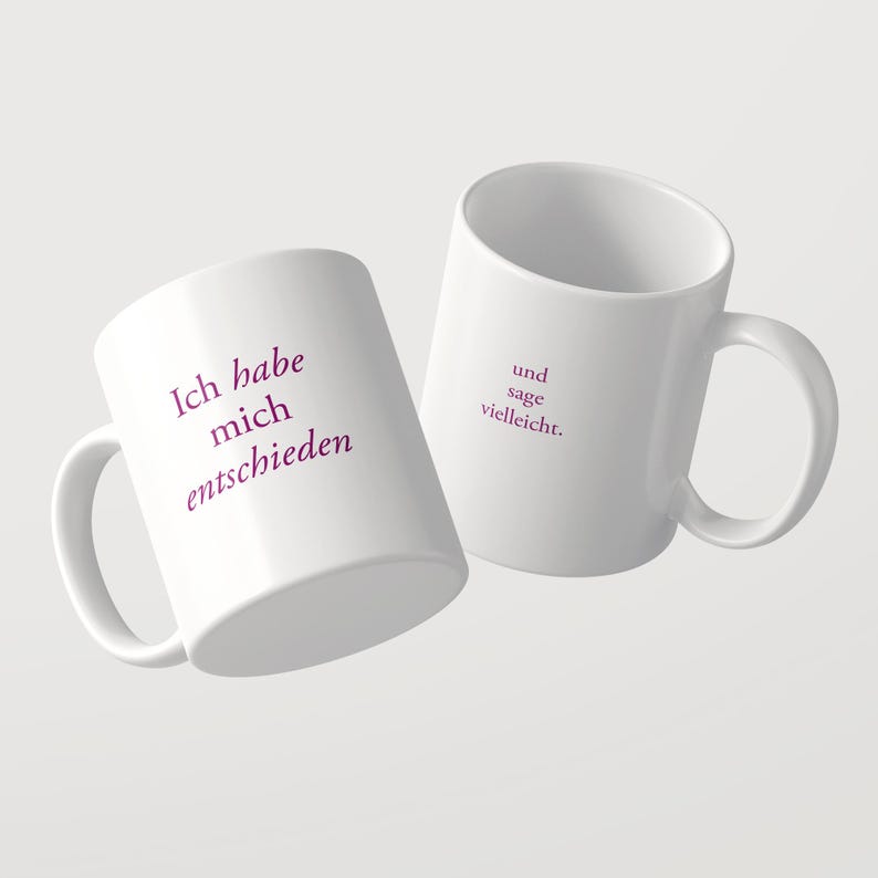 May include: Two white ceramic mugs featuring purple text. One mug displays the German phrase Ich habe mich entschieden, while the other mug displays the German phrase und sage vielleicht. Both mugs have a standard handle and cylindrical shape.