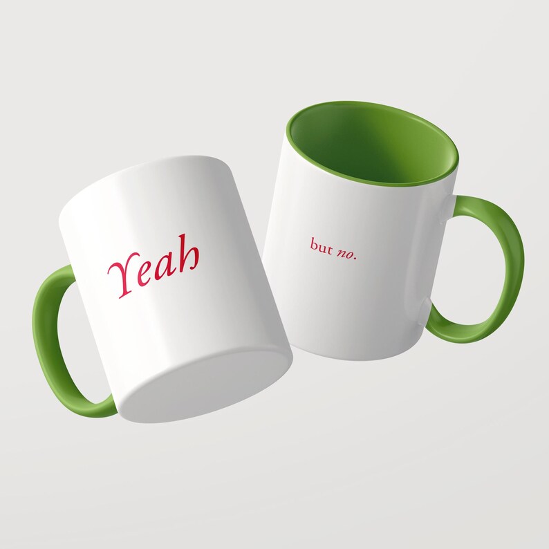 May include: Two white ceramic mugs with bright green handles and interiors. One mug features the word "Yeah" in red script, while the other displays the phrase "but no." in red lowercase letters. The mugs are positioned at an angle against a plain background.