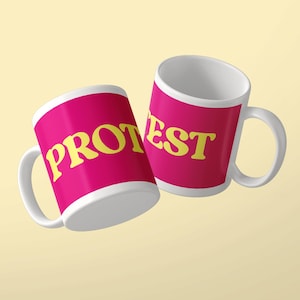 Puede incluir: Dos tazas de cerámica blanca con un fondo magenta vibrante y letras amarillas en negrita. La taza de la izquierda muestra el texto PROT y la de la derecha el texto EST, formando la palabra PROTEST al verlas juntas. Cada taza tiene un asa.