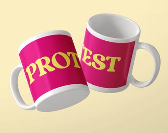 Może przedstawiać: Dwa białe ceramiczne kubki z żywym magentowym tłem i pogrubionymi żółtymi literami. Lewy kubek zawiera napis PROT, a prawy napis EST, co po złożeniu tworzy słowo PROTEST. Każdy z kubków posiada uchwyt do trzymania.