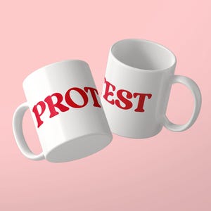Puede incluir: Dos tazas de cerámica blanca con letras rojas. La taza de la izquierda muestra el texto PROT y la de la derecha muestra el texto EST en una fuente serif negrita. Ambas tazas tienen un asa estándar y un acabado liso y brillante.