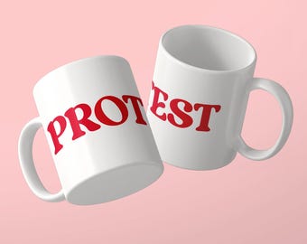 Może przedstawiać: Dwa białe kubki ceramiczne z czerwonym napisem. Lewy kubek zawiera tekst PROT, a prawy tekst EST pogrubioną czcionką szeryfową. Oba kubki mają standardowy uchwyt oraz gładkie, błyszczące wykończenie na jasnoróżowym tle.