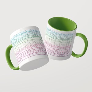 Pu&ograve; includere: Due tazze in ceramica bianca con manici e interni verde brillante. L'esterno di ogni tazza presenta linee orizzontali ripetute di testo con un gradiente arcobaleno, che riportano la scritta "don't give a shizz" in un carattere sans-serif.