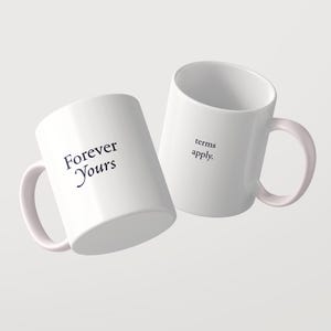 May include: Two white ceramic mugs with handles. One mug features the black text "Forever Yours" printed on the side. The second mug, positioned slightly behind and to the right, features the black text "terms apply." printed on the side.