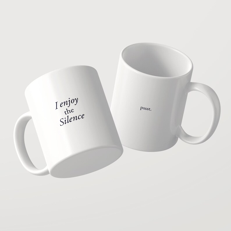 May include: Two white ceramic mugs with black text. One mug features the phrase "I enjoy the Silence" in a serif font. The second mug displays the word "pssst." in a smaller, simple font. Both mugs have a standard handle and cylindrical shape.