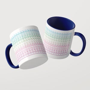 Pu&ograve; includere: Due tazze in ceramica bianca con manici e interni blu scuro. L'esterno di ogni tazza presenta un motivo orizzontale ripetuto con il testo "don't give a shizz" stampato in una sfumatura di colori che passa dal verde acqua al rosa.