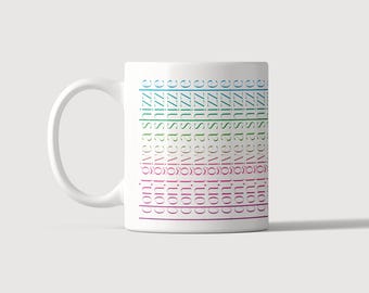 Puede incluir: Una taza de cerámica blanca con el texto repetido "don't give a shizzle" impreso en columnas verticales. El texto aparece en varios colores, incluyendo azul, verde, rosa y morado, dispuestos en un patrón de cuadrícula en el lateral de la taza.