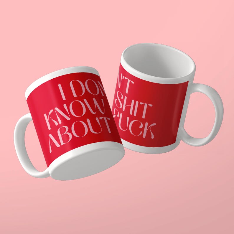 May include: Two white ceramic mugs with red exterior panels. The left mug features the white text I DON'T KNOW ABOUT. The right mug features the white text I DON'T SHIT FUCK. Both mugs have a curved handle and a smooth, glossy finish on the surface.
