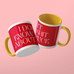 May include: Two ceramic mugs with a bright red exterior and a yellow interior and handle. The mugs feature white text that reads I DON'T KNOW ABOUT SHIT FUCK in a stylized font. The mugs are positioned at an angle against a solid light pink background.