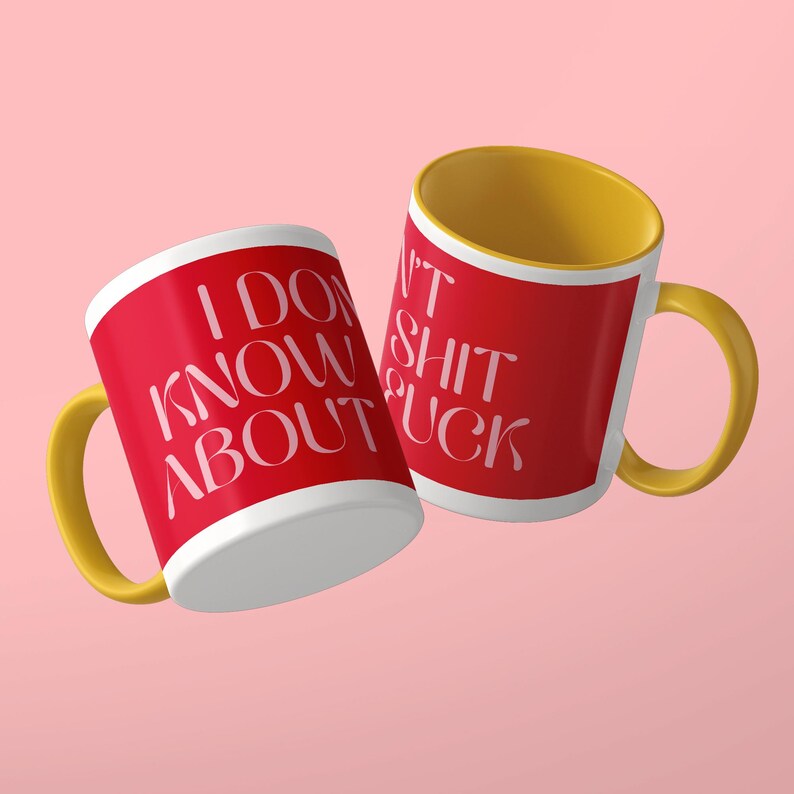 May include: Two ceramic mugs with a bright red exterior and a yellow interior and handle. The mugs feature white text that reads I DON'T KNOW ABOUT SHIT FUCK in a stylized font. The mugs are positioned at an angle against a solid light pink background.