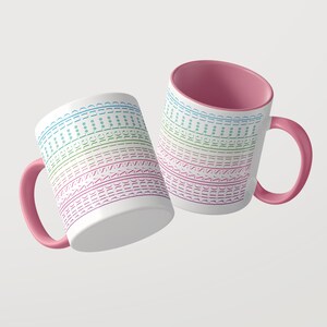 Puede incluir: Dos tazas de cer&aacute;mica blanca con asas e interiores de color rosa. El exterior presenta l&iacute;neas horizontales repetitivas con el texto sunshine en un degradado de azul, verde y morado, intercaladas con peque&ntilde;os s&iacute;mbolos de asterisco en un patr&oacute;n.