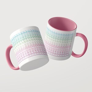 Pu&ograve; includere: Due tazze in ceramica bianca con interni e manici rosa. L'esterno presenta un motivo orizzontale ripetuto del testo "con. i. give a shizz" in una sfumatura di colori blu, verde e viola, disposti in diverse righe sovrapposte.