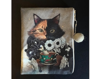 May include: A black and orange cat with a white patch on its face is wearing a black lace collar and holding a green teacup with a white bird inside. The cat is surrounded by white flowers and the background is a light gray with a subtle sparkle.