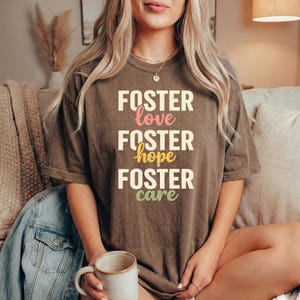 May include: A white ceramic mug with a black handle and the text "But First, Coffee" in a bold, black font. The mug is set against a blurred background, suggesting a cosy setting.
