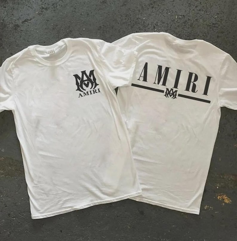 Puede incluir: Dos camisetas blancas con logotipos AMIRI negros. Una camiseta tiene el logotipo en la parte delantera y la otra tiene la palabra "AMIRI" en la espalda. Las camisetas est&aacute;n hechas de un material suave y ligero.