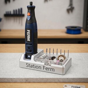 Peut inclure: Un outil rotatif Ferm bleu et noir avec un support d'accessoires argenté "Station Ferm". Le support contient divers embouts et accessoires. L'outil est sur un établi avec des outils en arrière-plan.