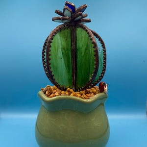 Stained glass succulent cactus, with blue flower and green ceramic pot.