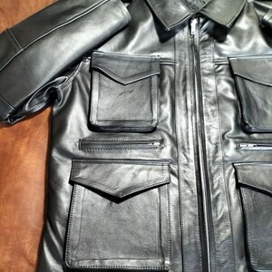 May include: Black leather jacket featuring multiple pockets and a zip closure. The jacket has a collared neckline and a classic design. The sleeves are folded over, and the leather appears smooth. A stylish outerwear piece, suitable for various occasions.