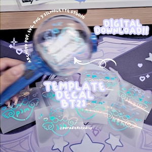 May include: A blue and white light stick is held over several clear decal templates with teal and white designs. The text "TEMPLATE DECAL BT21" and "DIGITAL DOWNLOAD!!" are visible. The background is a purple and white pattern.