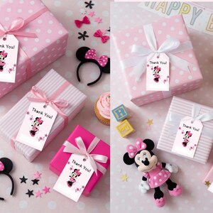 May include: Pink gift boxes with white polka dots and stripes, tied with pink ribbons. Each box has a tag that says "Thank You!" with a Minnie Mouse graphic. Decorative elements include a Minnie Mouse headband, stars, and a Minnie Mouse doll.