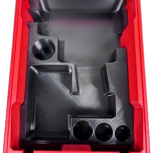 May include: A red plastic tool case with a black interior. The interior features moulded compartments and circular holes of varying sizes. The case is open, revealing the internal structure designed for organisation and storage.