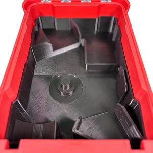 May include: A red plastic storage container with a hinged lid, open to show a black interior with compartments. The interior has a central raised circular element and dividers, for organised storage.