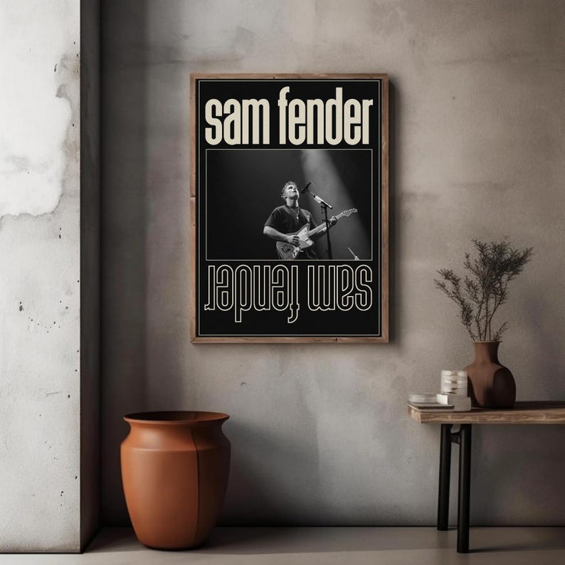Puede incluir: Un p&oacute;ster en blanco y negro enmarcado con el texto "sam fender" en blanco. El p&oacute;ster incluye una fotograf&iacute;a de un m&uacute;sico tocando la guitarra en el escenario. El texto "sam fender" tambi&eacute;n est&aacute; impreso al rev&eacute;s en la parte inferior.